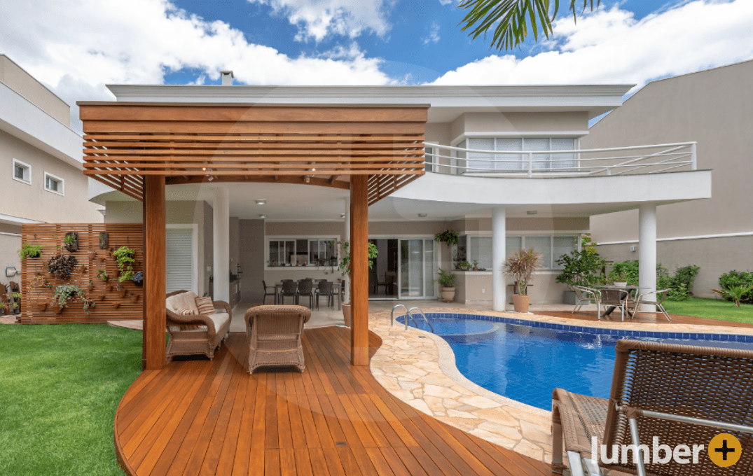 Wood decking wraps around the edge of a pool and under a pergola.
