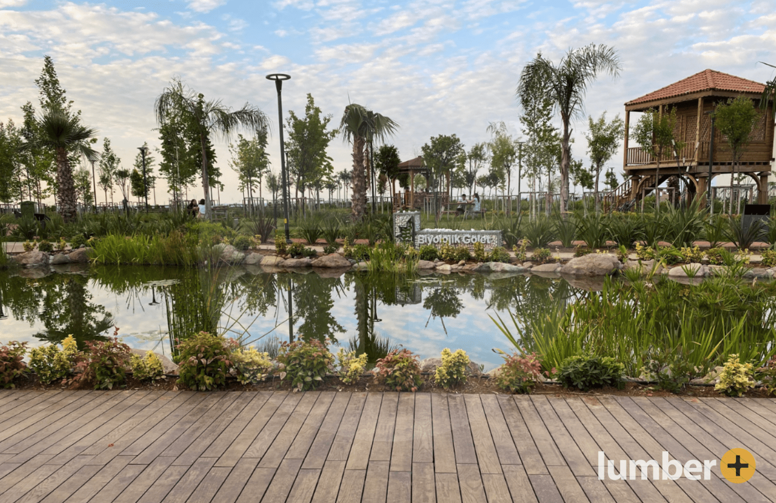 a community center design with tropical hardwood deck near a small pond