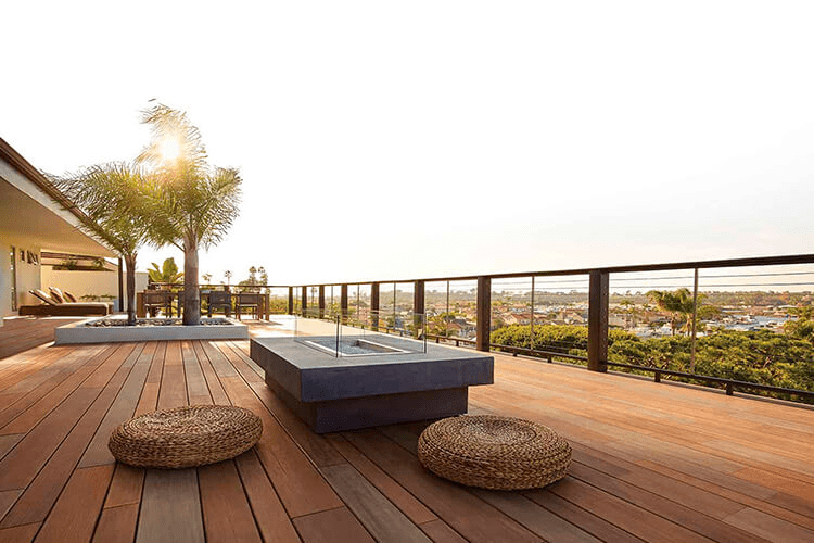 A composite deck with palm trees and a built-in fireplace 