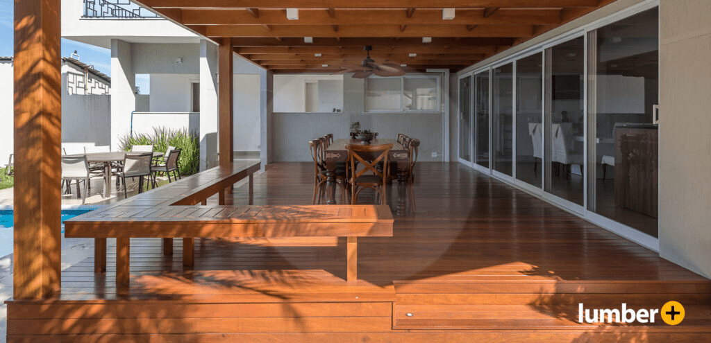 Open area wooden deck outdoor dining area next to a pool.