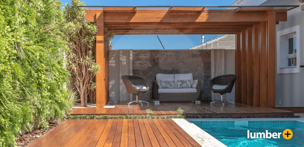 Warm red wooden decking and pergola next to a swimming pool