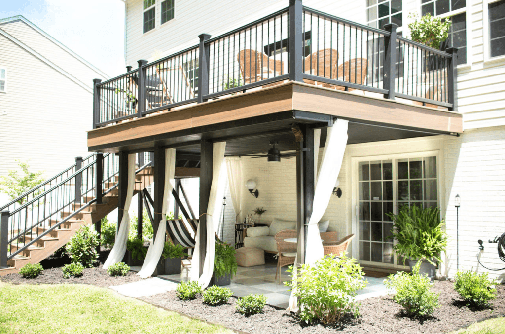 Elevated Trex deck with stairs to the yard, a sitting area beneath, and integrated curtains for shade and privacy.