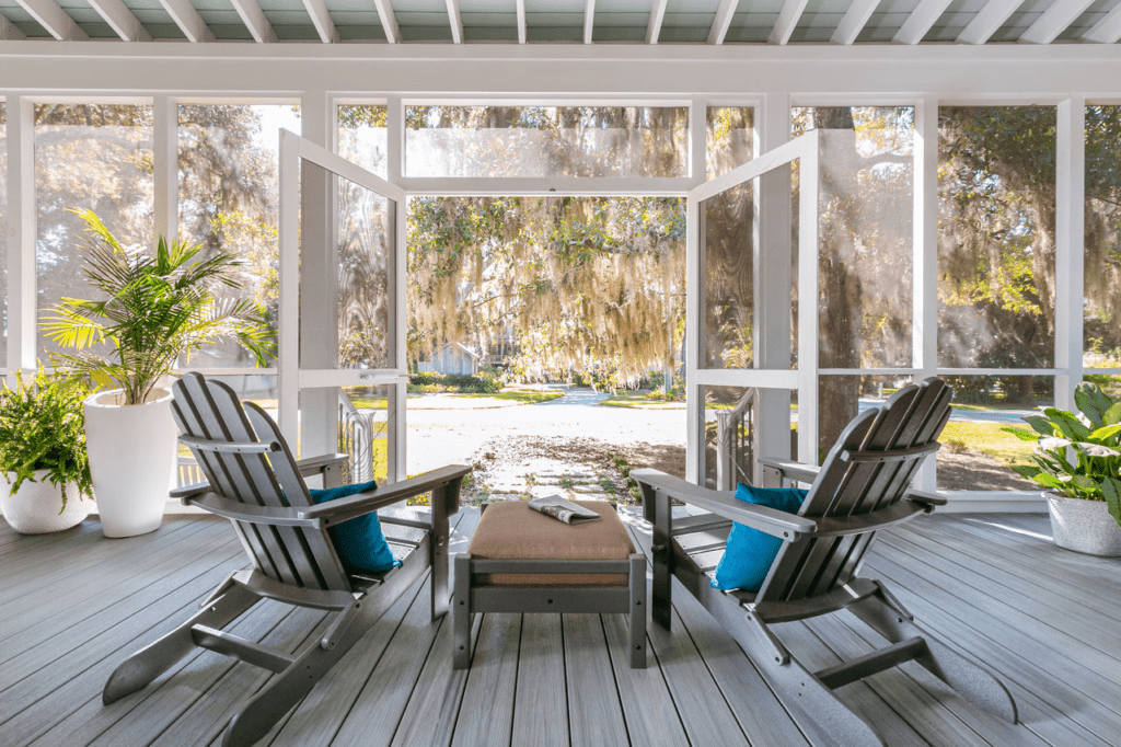 Trex enclosed porch with glass walls and doors that open to the yard, creating a cozy space with clear outdoor views.