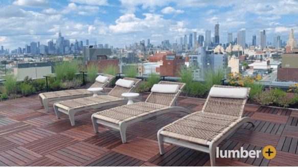 Hardwood deck tiles underneath lounge chairs on the rooftop in the city.