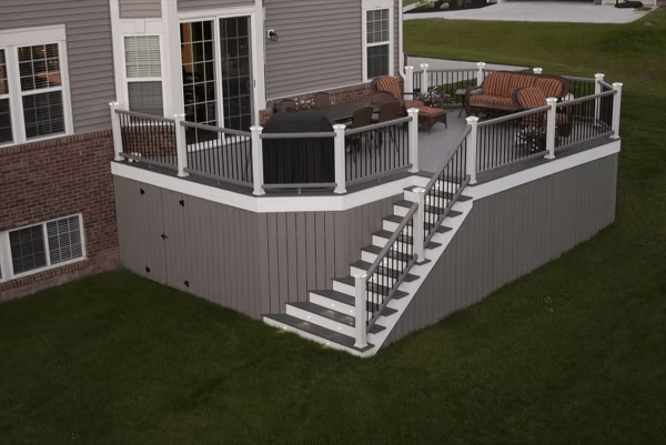 Trex deck skirting with full-length panels and a storage access door by Woodland Deck Company, offering privacy and utility.