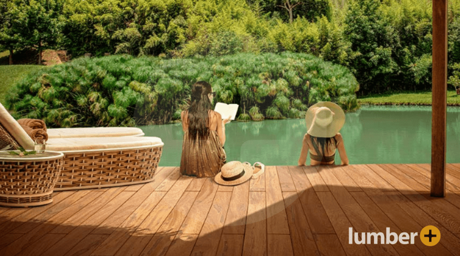 Two women sit on an outdoor wood deck enjoying the sun.