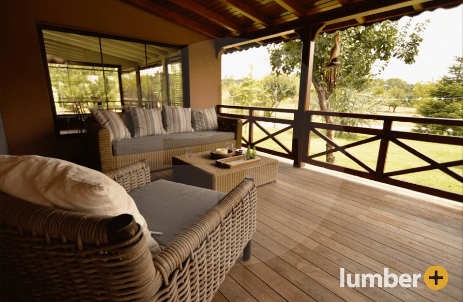 A fire resistant deck with light brown deck furniture underneath a wooden ceiling.