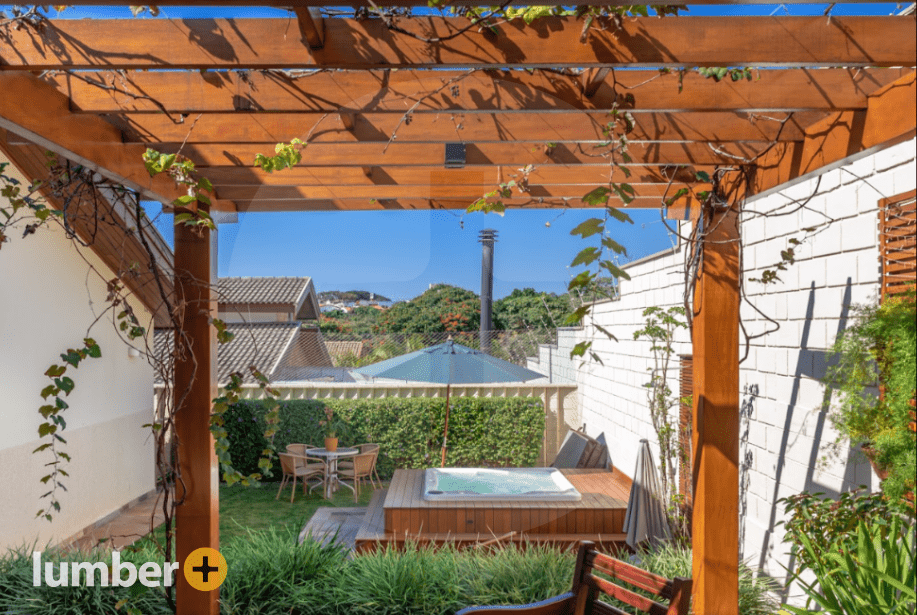 Wood pergola in a small backyard with a wood clad decking around a hot tub.