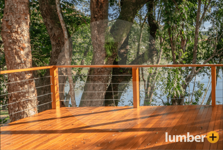 A wooden deck with wood railings and posts with horizontal cable balusters.