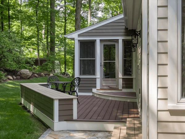 Backyard deck with Trex Transcend® Spiced Rum decking, a screened porch, curved step, and built-in seating for outdoor relaxation.