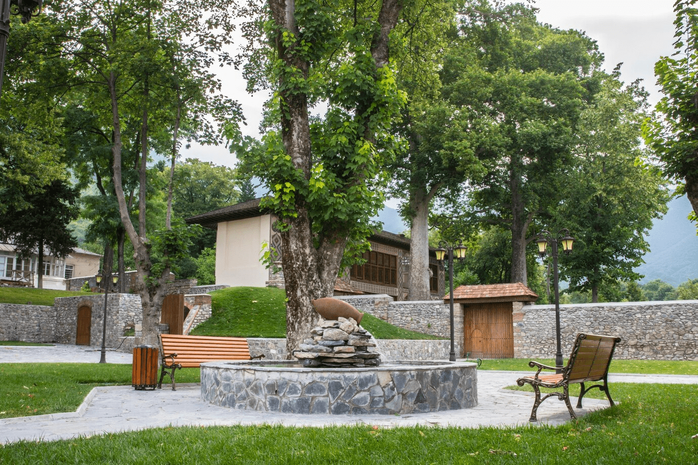 Stone water feature on a stone walkway with park benches.