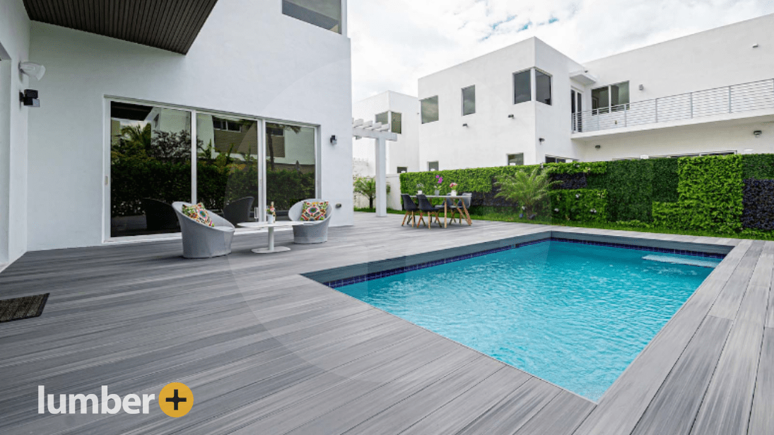 A gray PVC pool deck with a privacy fence made out of shrubbery.