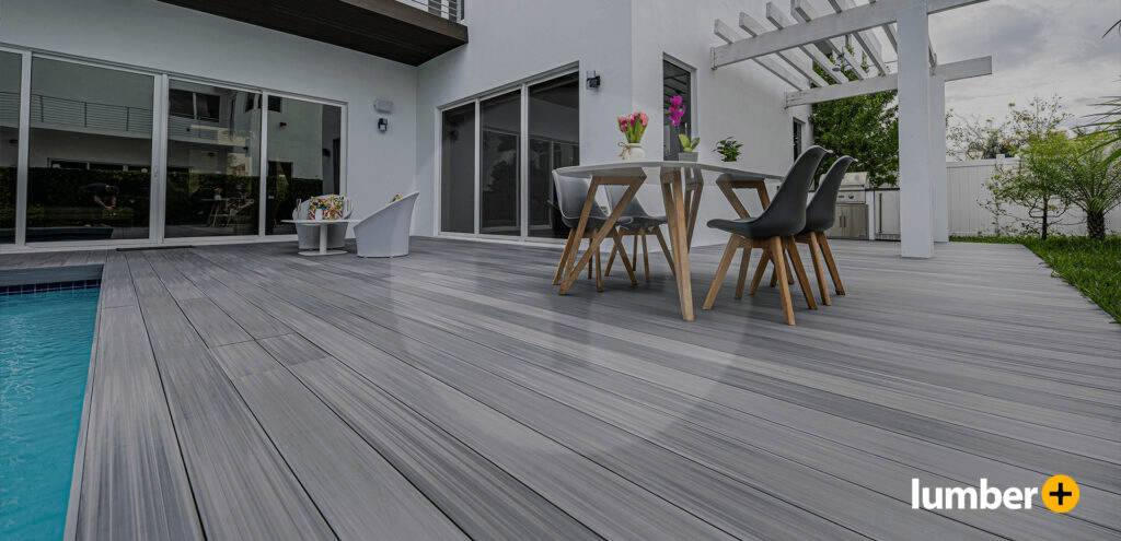 Light gray decking next to a house’s small square pool.