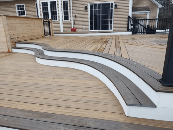 Elegant steps with curved Trex decking enhance a backyard deck.
