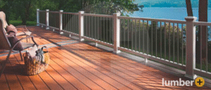 An outdoor deck that is up to code with a white railing as it overlooks a lake.