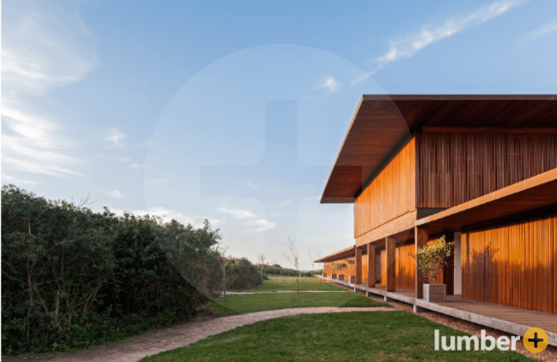 An image of a large wood-clad home with vertical siding and a wide porch under a blue sky.